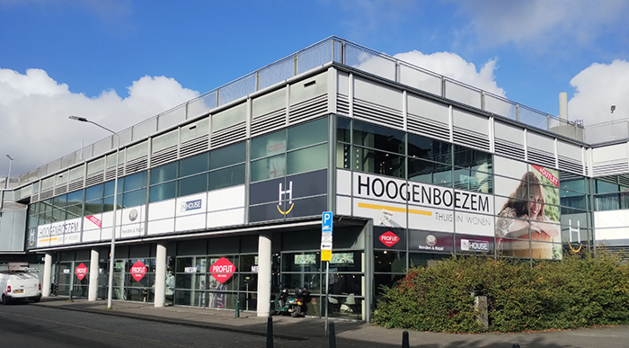 Hoogenboezem woonwinkel in Den Haag, gevestigd in een modern hoekpand met grote glazen ramen en de naam Hoogenboezem op de gevel.